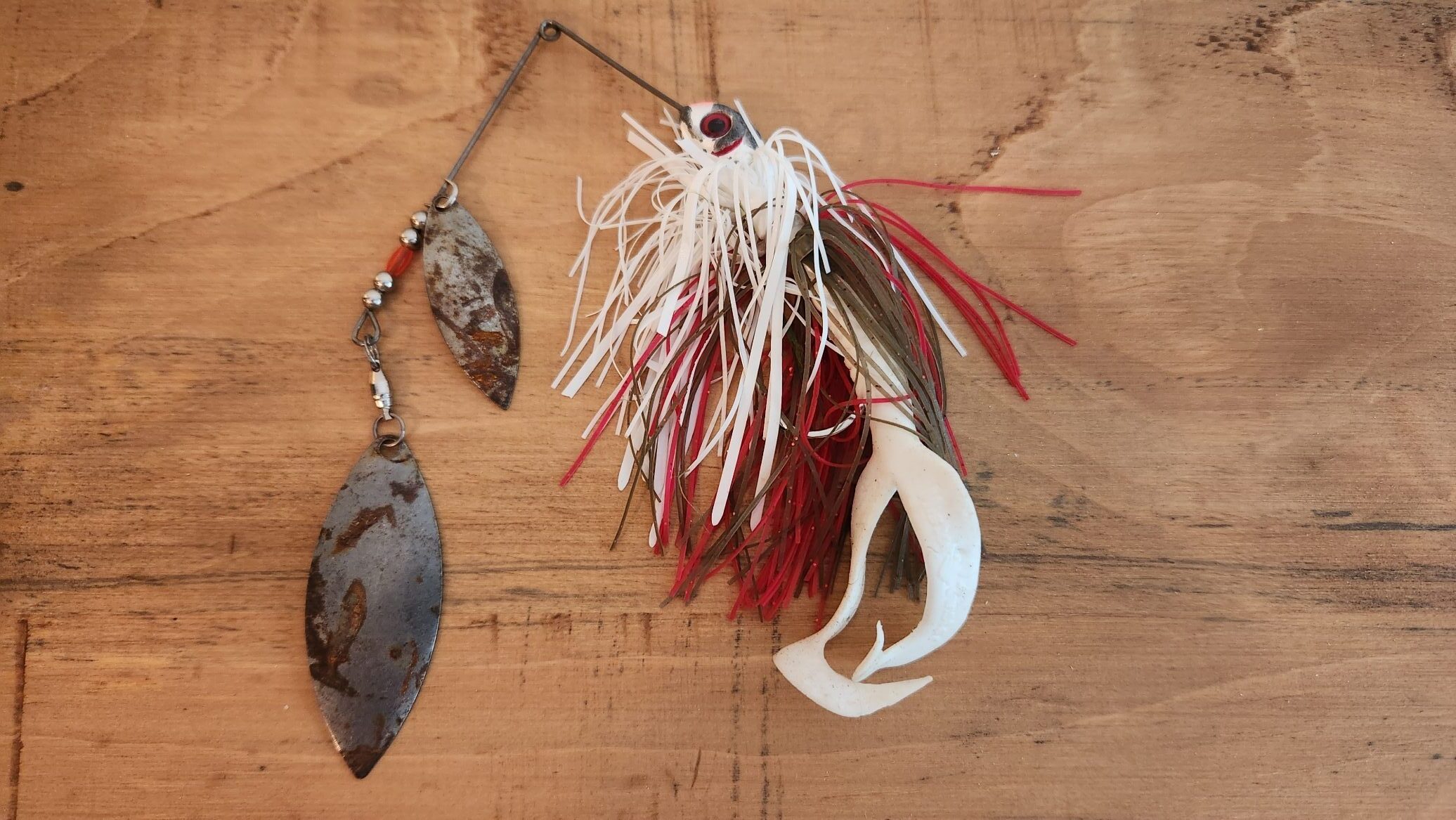 Spinnerbait lure with willow leaf spoon. White with white and red skirt. Two-tailed worm leader.